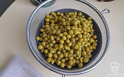 Откройте банку с горошком без сахара. Откиньте содержимое в дуршлаг, дайте жидкости стечь. 