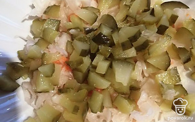 Положить в салатник капусту и мелко нарезанные соленые огурцы. 