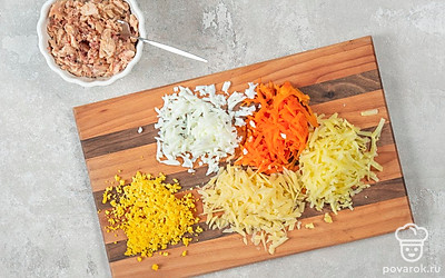 Достаньте консервированную горбушу из банки, слейте лишнюю жидкость, а саму рыбу разомните вилкой. Натрите на крупной терке морковь, картофель и сыр. Разрежьте яйца пополам, желтки отделите от белков, натрите их на терке отдельно друг от друга.