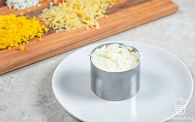 Поставьте на тарелку кулинарное кольцо. Выложите все ингредиенты слоями, промазывая их майонезом и посыпая солью. Первым слоем положите картофель, далее — горбушу, морковь, сыр и яичные белки. В конце посыпьте салат тертыми желтками.