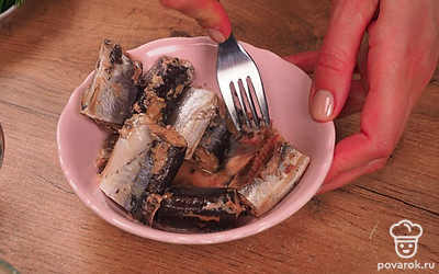 Подготовьте остальные продукты. Выложите рыбные консервы в миску и разомните их вилкой. Натрите на средней терке сыр. Лук мелко порубите. Достаньте масло из морозилки и натрите на крупной терке.