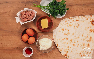 Отварите яйца вкрутую. Вымойте и мелко нарежьте зелень. Натрите сыр. Почистите яйца и натрите на терке. Консервированный тунец достаньте из банки, разомните на плоской тарелке. Лаваш разрежьте на три прямоугольника одного размера.