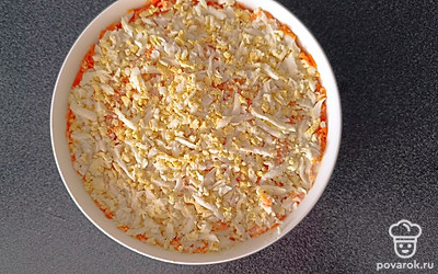 Натрите на терке вареные яйца. Выложите сверху. Накройте салатник пищевой пленкой, уберите салат в холодильник на 2 часа.