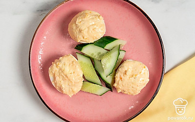 Выложите закуску на тарелку. Украсьте ее дольками огурца, а затем подайте на стол.