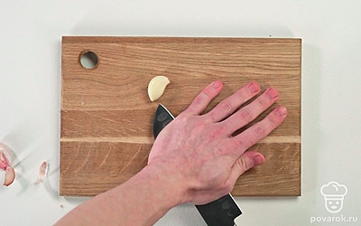 Положив плашмя нож, раздавите зубчики чеснока.