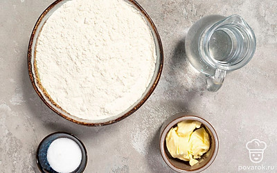 Просейте муку через мелкое сито, чтобы лепешки получились более мягкими. Разогрейте воду до теплого состояния. Подготовьте пищевую пленку, скалку и сковороду с антипригарным покрытием.
