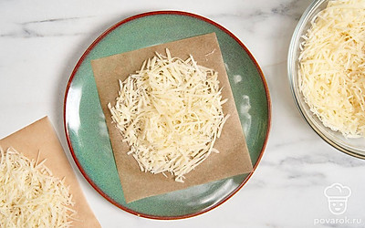 Выложите на тарелку 1 квадратик пергамента. Сверху разложите часть сыра, формируя круг. Уберите тарелку в микроволновку на 20-30 секунд.