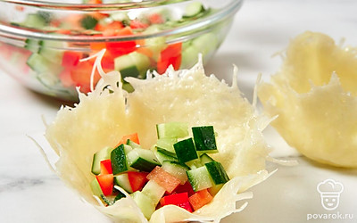 Нарежьте овощи небольшими кубиками. Наполните ими сырные корзиночки.