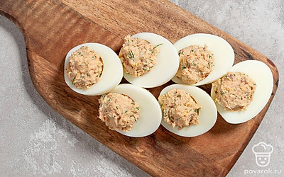 Положите к горбуше майонез, всыпьте черный перец, рубленые лук и укроп. Хорошо перемешайте до образования однородной массы. Равномерно распределите начинку по половинкам белков, выровняйте верхушку в виде аккуратной небольшой «горки».