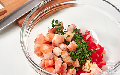 Очистите помидор от семян, уберите водянистую часть, нарежьте мелкими кубиками. Измельчите петрушку и чеснок. Добавьте ингредиенты в миску с креветками.