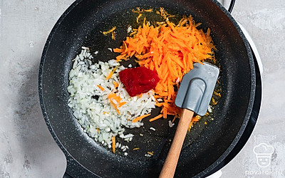 Мелко покрошите репчатый лук, а также натрите морковь. Разогрейте на сковороде растительное масло. Обжарьте лук с морковью на среднем огне в течение 5 минут, регулярно перемешивая. После этого добавьте томатную пасту и готовьте зажарку еще 5 минут.