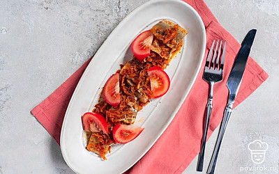 Выложите ломтики сельди на тарелку. Украсьте подачу дольками помидора.