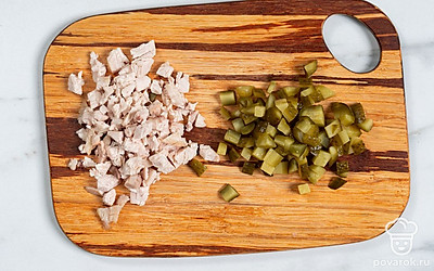 Положите куриное филе в кипящую подсоленную воду. Варите 40 минут. Остудите и мелко нарежьте. Так же измельчите соленый огурец.