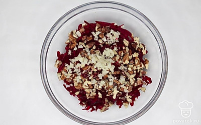 Поместите свеклу в миску, добавьте подготовленные орехи, кунжут, нарезанный чеснок. Аккуратно перемешайте. Добавьте половину майонеза и перемешайте салат еще раз. Выложите в тарелку для подачи и украсьте оставшимся майонезом.