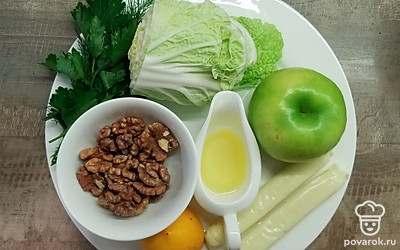 Удалите у пекинской капусты наружные листья, если они загрязнены или повреждены. Вымойте яблоко и зелень, выдавите сок из лимона, крупно порубите грецкие орехи и зелень. Приготовьте одно большое блюдо или две порционные тарелки.
