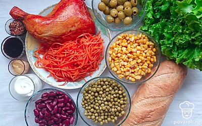 Батон нарежьте кусочками небольших размеров. Также нарежьте куриный окорок и разрежьте оливки с маслинами пополам. Тщательно промойте листья салата.