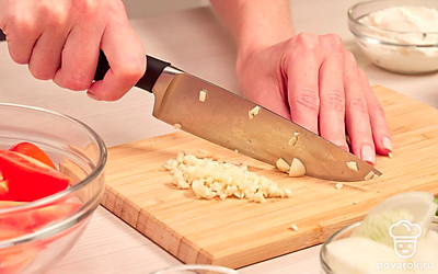 Измельчите овощи. Нарежьте огурцы кружками, а затем каждый кружок разрежьте на половинки. Помидоры нарежьте дольками. Лук нашинкуйте тонкими полукольцами, чеснок мелко порежьте.