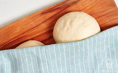 Разделите тесто на 2 части. Сформируйте из каждой половины теста шарик. Выложите его на рабочую поверхность, накройте салфеткой или полотенцем. Оставьте заготовки на 30 минут.