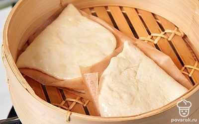Вырежьте из пергамента 4 квадрата. Каждый шарик теста раскатайте в тонкую лепешку в форме овала. Смажьте растительным маслом и сложите пополам, положив внутрь лист пергамента. Еще по листу положите под булочки в чашу пароварки. Готовьте булочки на пару 40 минут.