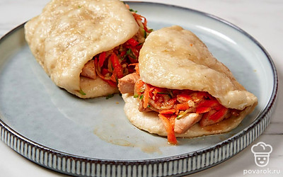 Крупно нарежьте готовую курицу. В каждую булочку положите ломтики мяса и салат, а сверху полейте соусом.