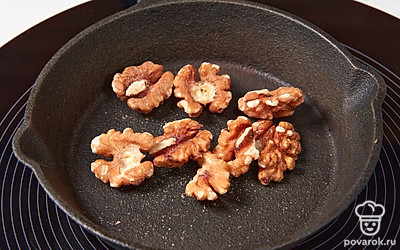 Разогрейте сухую сковороду. Выложите в нее грецкие орехи. Подсушите их в течение 5 минут, помешивая, а затем остудите и измельчите.