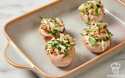 Разогрейте духовку до 200℃. Наполните шляпки грибов начинкой, выложите в форму, смазанную маслом, и уберите в духовку на 8-10 минут до полной готовности.